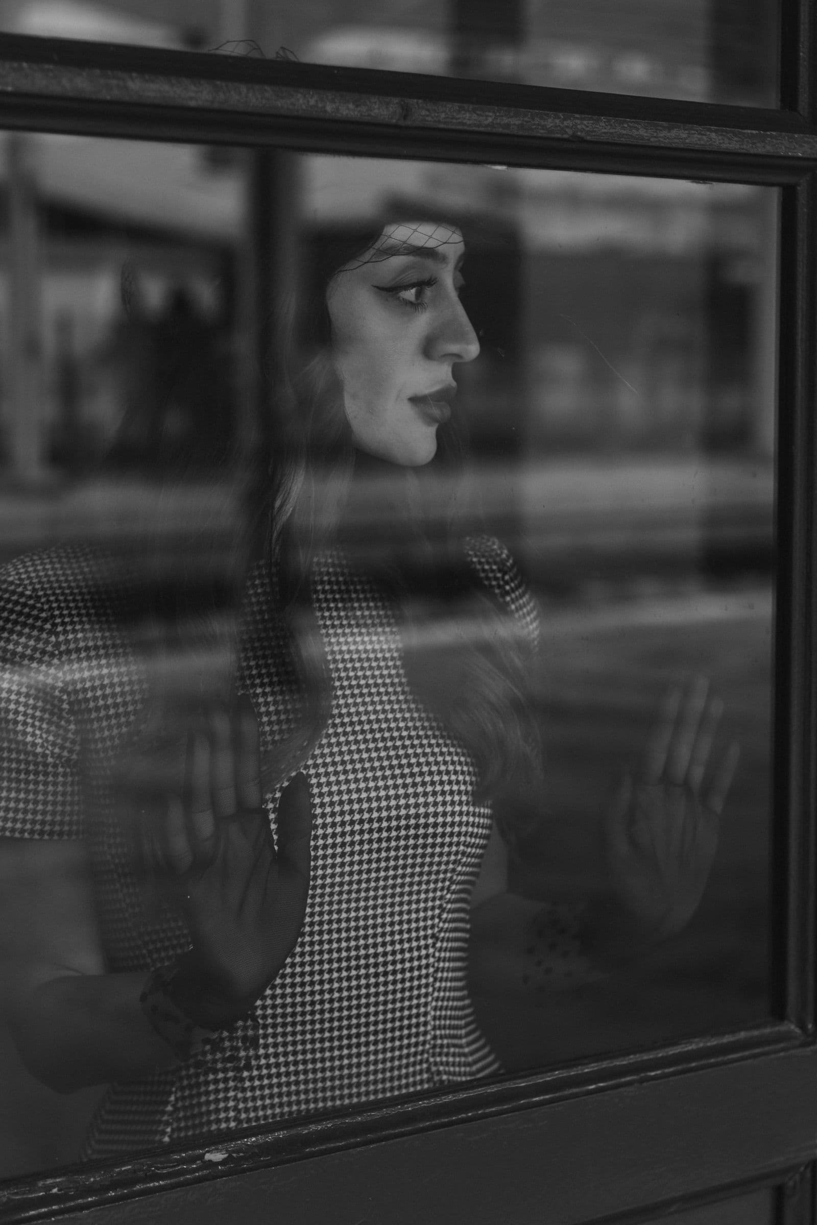 Mulher olhando pela janela, em preto e branco